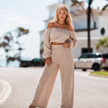 Woman in a beige outfit standing on a street with blurred background