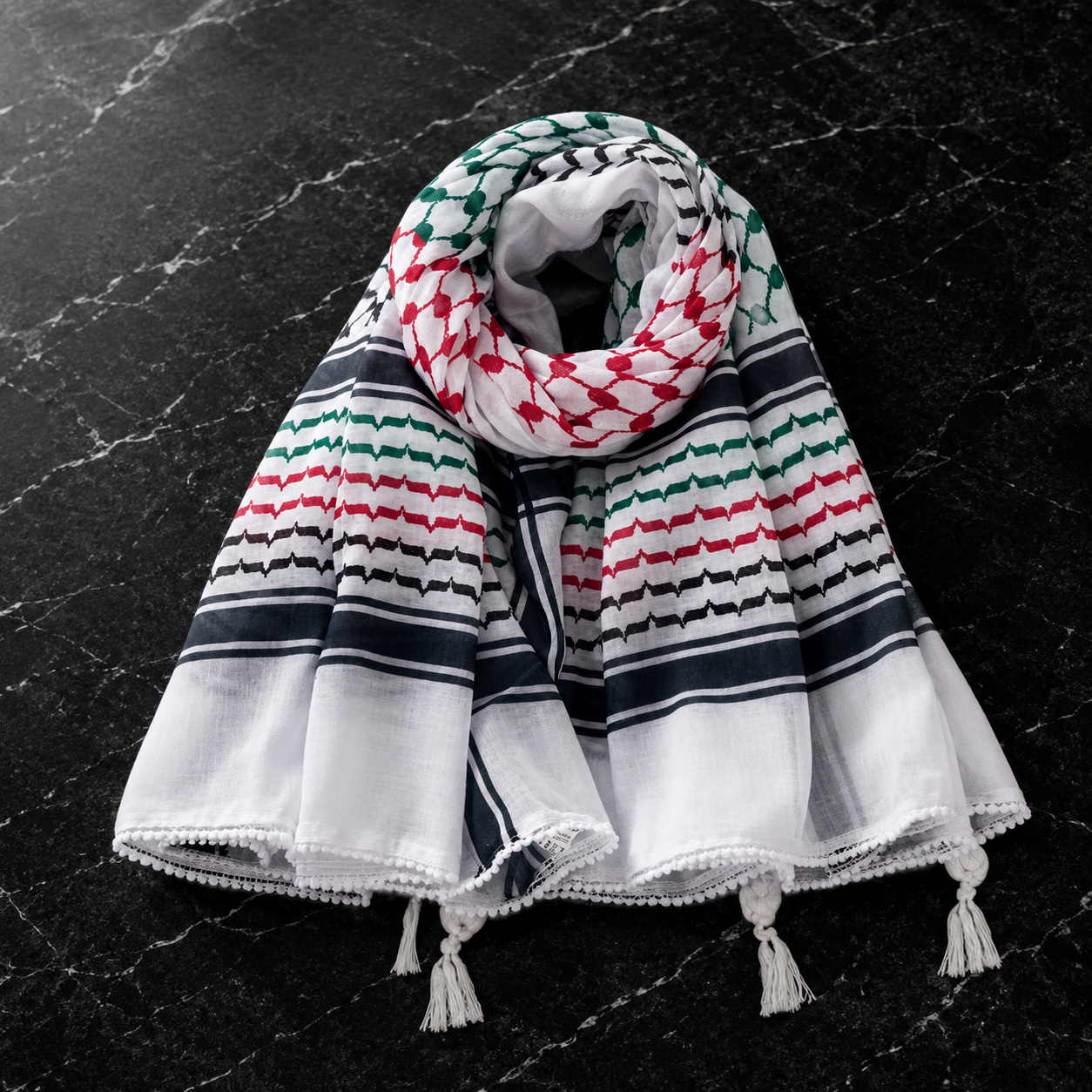 Colorful patterned scarf with tassels on a black marble surface