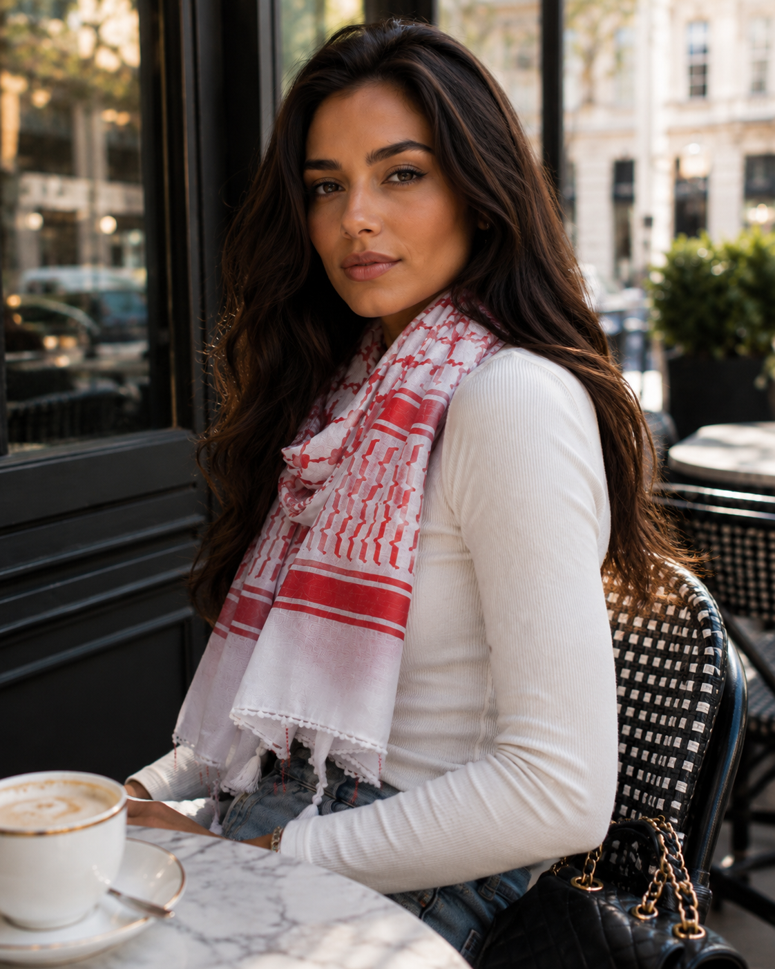 Woman sitting at an outdoor cafe wearing a red and white scarf