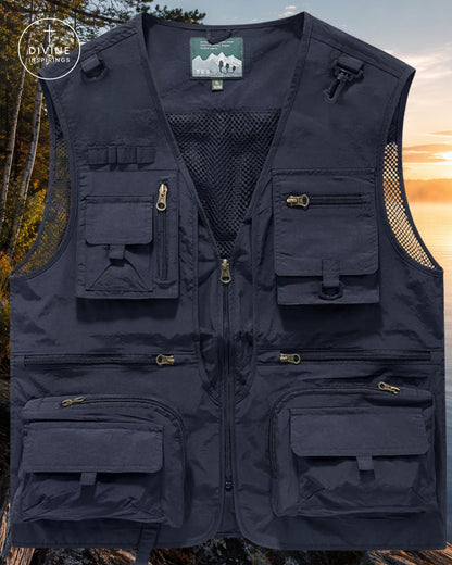A dark navy blue multi-pocket utility vest with a front zipper, mesh lining, and gold-toned zipper pulls, shown against a blurred outdoor forest background at sunset. A circular 'DIVINE INSPIRINGS' brand logo is visible in the top-left corner.
