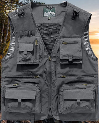 A gray multi-pocket utility fishing vest with mesh side panels and a front zipper, shown flat against a blurred outdoor forest and sunset background. A circular 'DIVINE INSPIRINGS' brand logo is visible in the top-left corner.