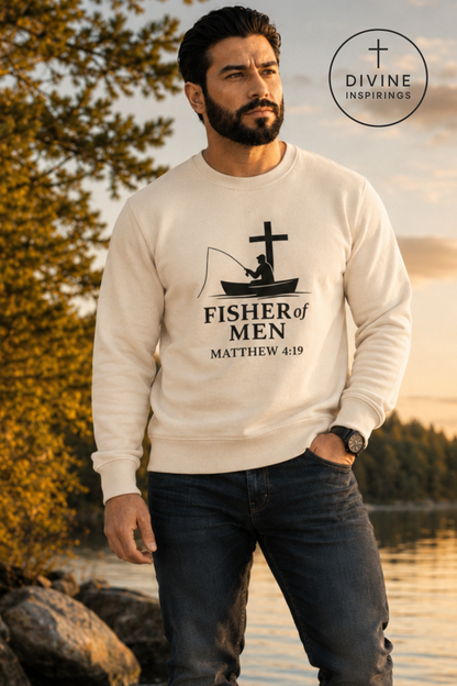 A man standing outdoors by the water at sunset wearing a cream-colored crewneck sweatshirt with a black graphic of a fisherman and cross, with the text 'FISHER of MEN MATTHEW 4:19'. A 'DIVINE INSPIRINGS' logo is visible in the top right corner.