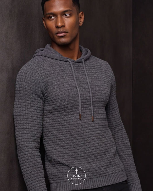 A man wearing a dark gray ribbed knit hoodie sweater, posed against a dark textured studio background. A circular 'DIVINE INSPIRINGS' logo watermark is visible at the bottom center.