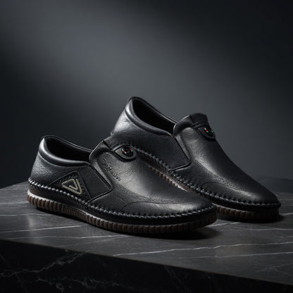 Pair of black leather shoes on a dark surface with a dark background