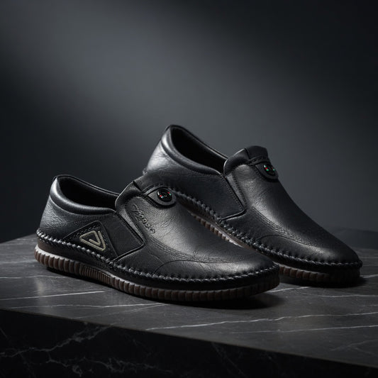 Pair of black leather shoes on a dark surface with a dark background
