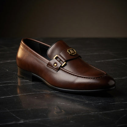 Brown leather loafer with a gold buckle on a dark surface