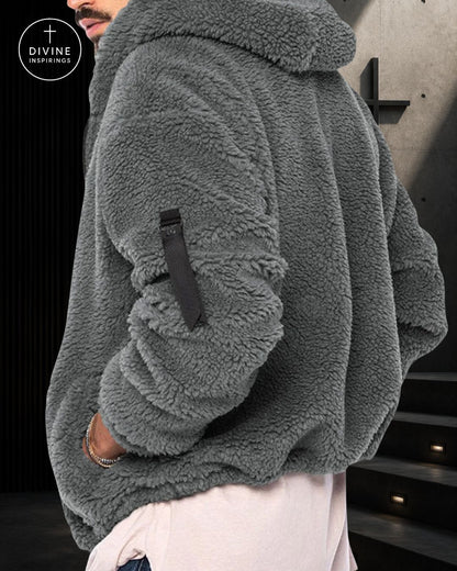 A close-up of a person wearing a gray sherpa fleece hooded jacket with a black strap detail on the sleeve, paired with light pink pants. The DIVINE INSPIRINGS logo is visible in the top-left corner.
