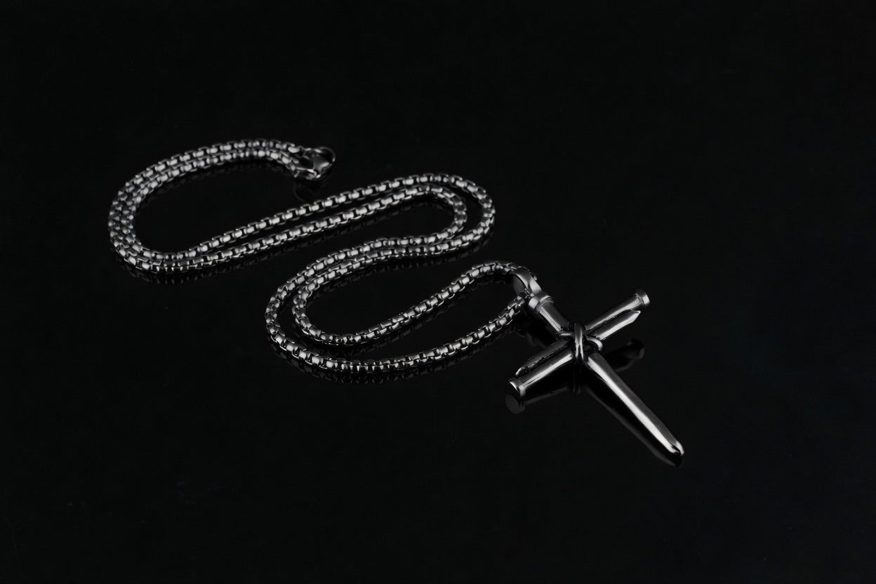 Silver chain necklace with a cross pendant on a black background