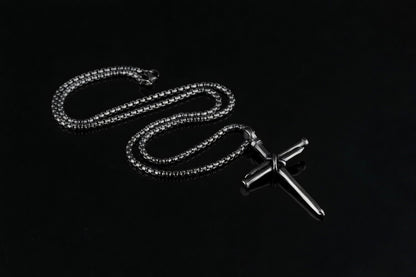 Silver chain necklace with a cross pendant on a black background