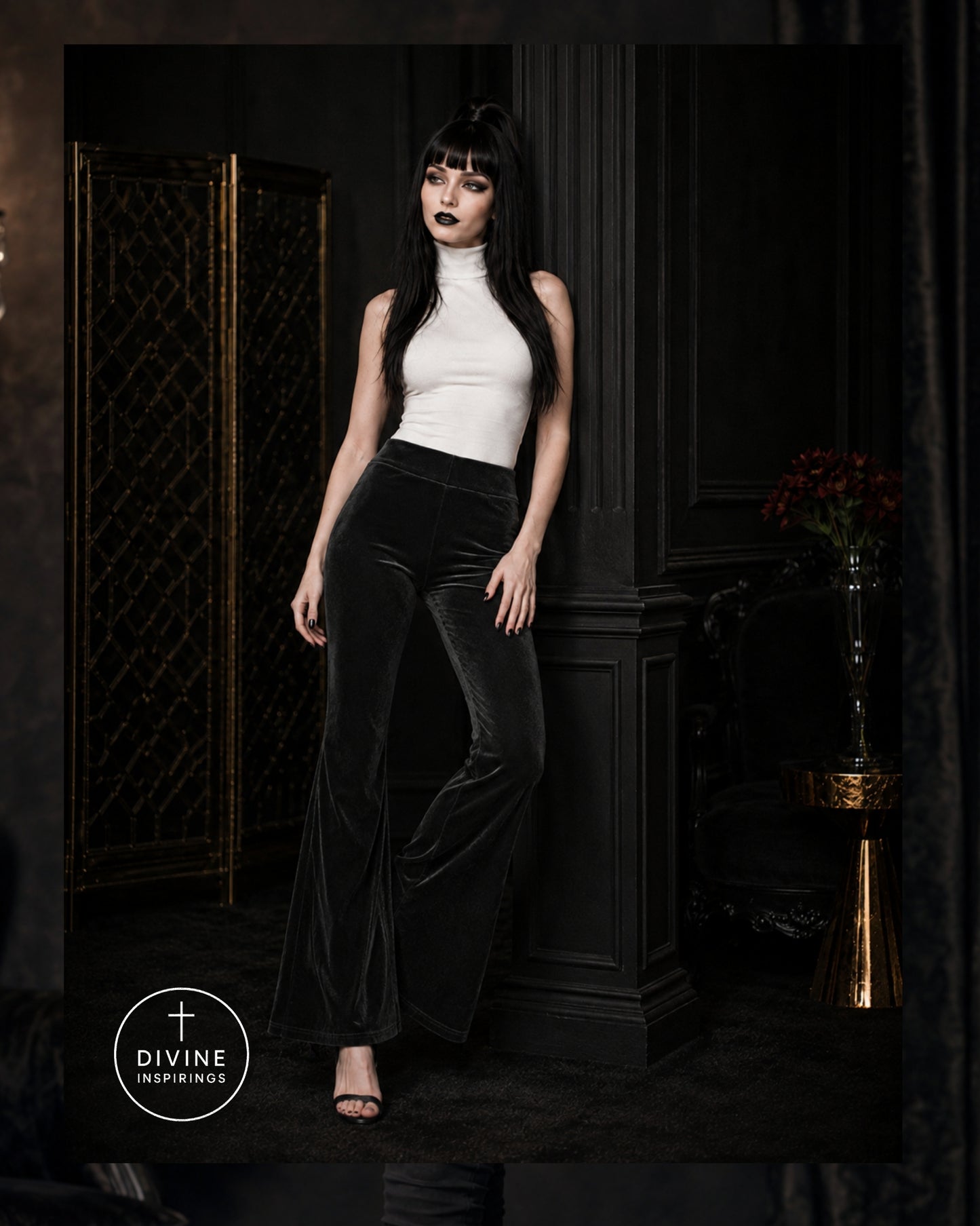 A model with long black hair and dark makeup stands in a dark interior wearing a white sleeveless mock-neck top and black velvet flare pants. A circular 'DIVINE INSPIRINGS' logo is visible in the lower-left corner.