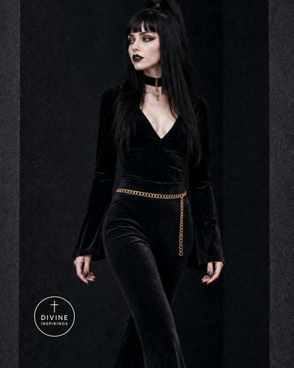 A gothic-style model with long black hair and black eye makeup wears a black velvet long-sleeve jumpsuit with a gold chain belt. She is posed against a dark textured studio background with a 'DIVINE INSPIRINGS' logo in the bottom-left corner.