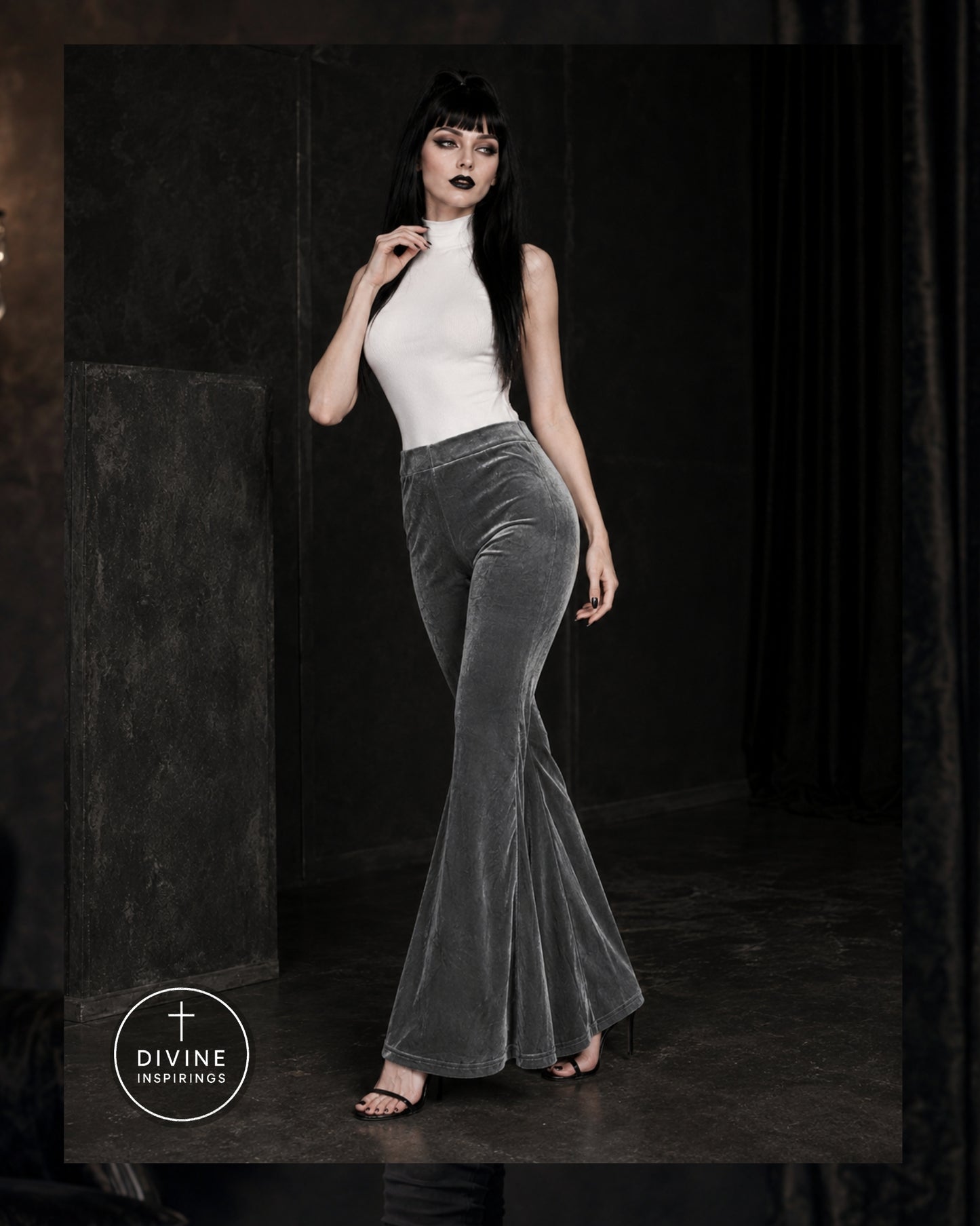 A model wearing a white sleeveless mock-neck top and high-waisted, flared gray velvet pants, standing in a dark, moody studio setting. The DIVINE INSPIRINGS brand logo is visible in the bottom-left corner.