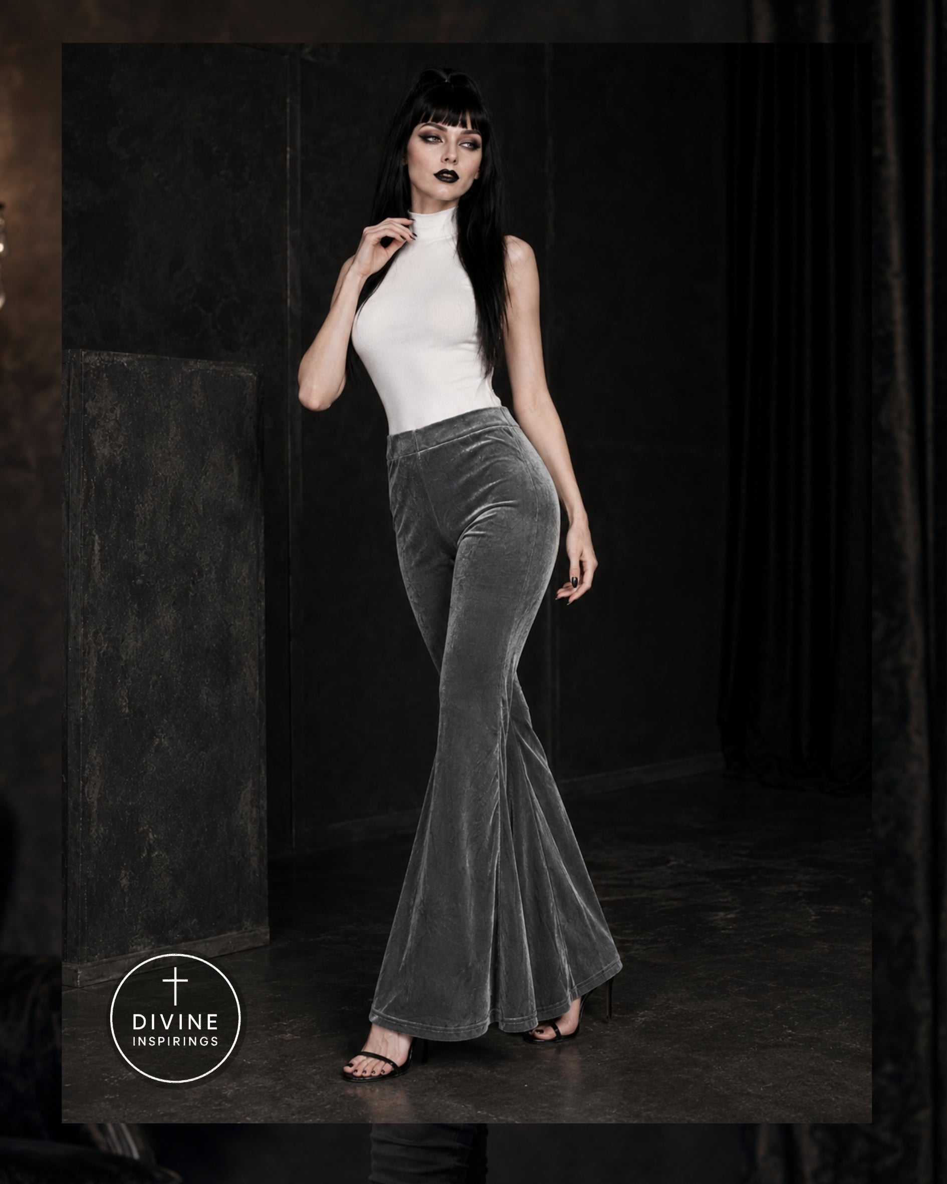 A model wearing a white sleeveless mock-neck top and high-waisted, flared gray velvet pants, standing in a dark, moody studio setting. The DIVINE INSPIRINGS brand logo is visible in the bottom-left corner.