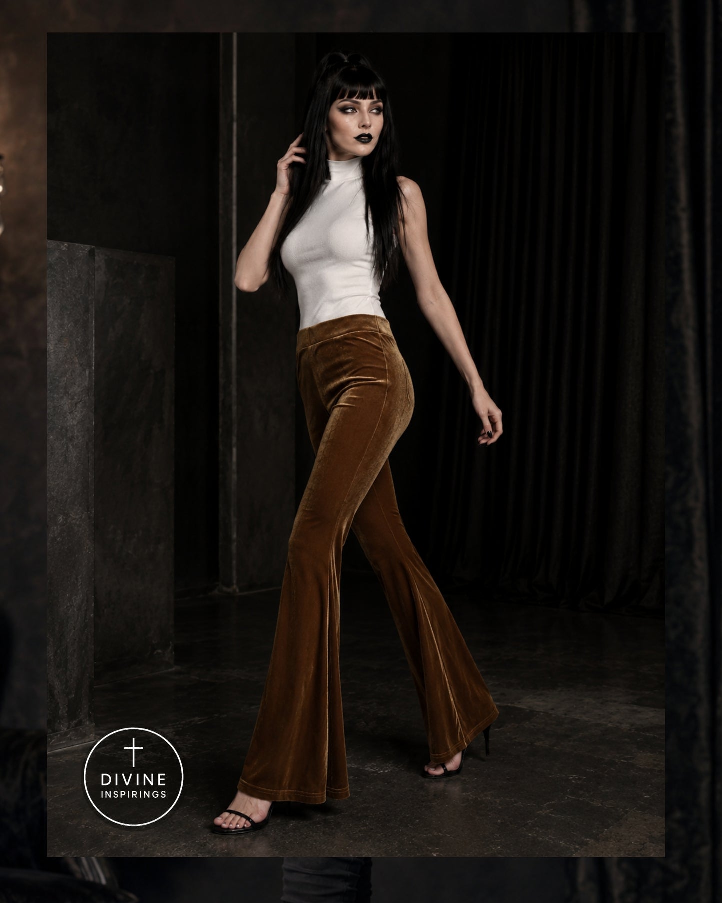 A model wearing a white mock-neck top and brown velvet flare pants walks in a dark studio setting. A circular logo for 'DIVINE INSPIRINGS' is visible in the bottom-left corner.