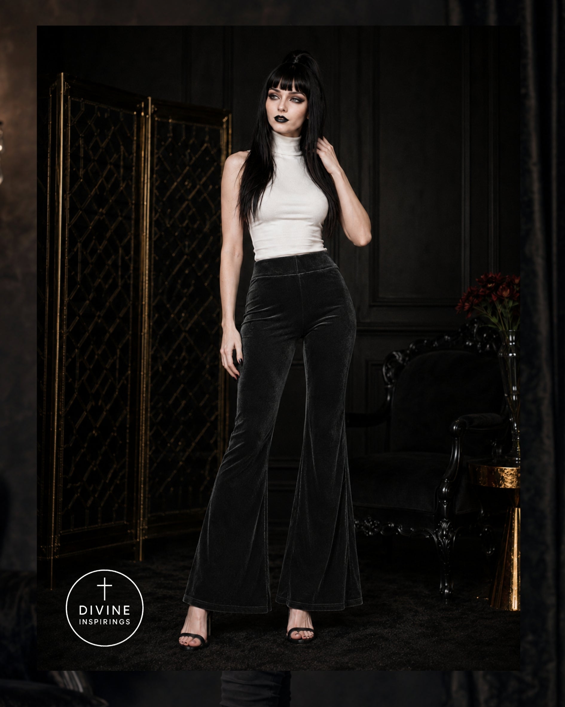 A woman modeling high-waisted black velvet flare pants with a white mock-neck top in a dark, elegant room with a gold folding screen.