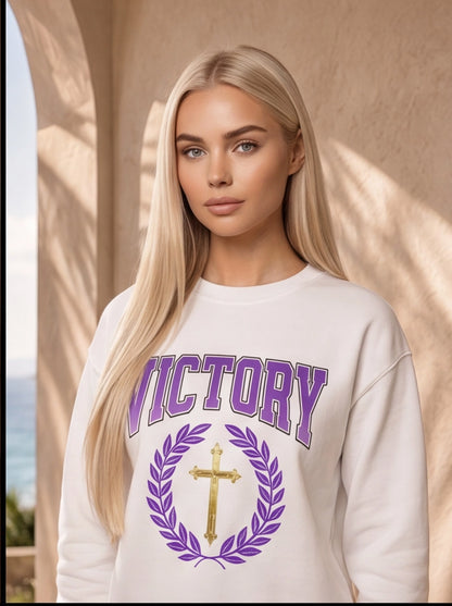 Woman wearing a white sweatshirt with 'VICTORY' and a cross design.