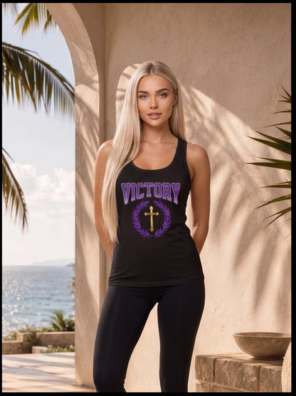 Woman wearing a black tank top with 'VICTORY' and a cross design, standing outdoors with palm trees and ocean view.