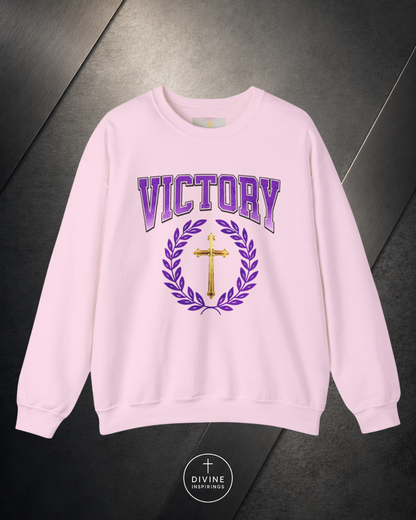 Pink sweatshirt with 'Victory' and cross design on a dark surface, featuring the brand 'Divine'.
