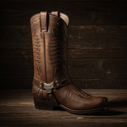 Brown leather cowboy boot with embossed design on a wooden surface and background
