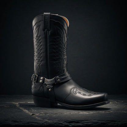 Black cowboy boot with leather strap on a dark background