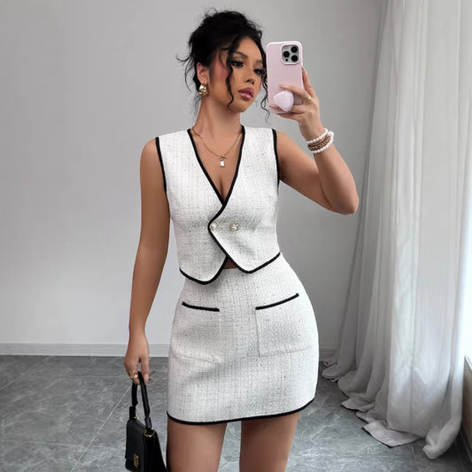 Woman taking a mirror selfie wearing a white outfit with black trim.