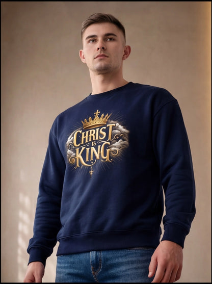 Man wearing a navy blue sweatshirt with 'Christ is King' text and crown graphic against a beige background