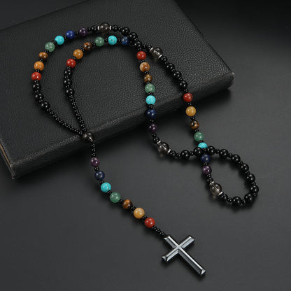 Multicolored beaded necklace with a silver cross pendant on a dark surface
