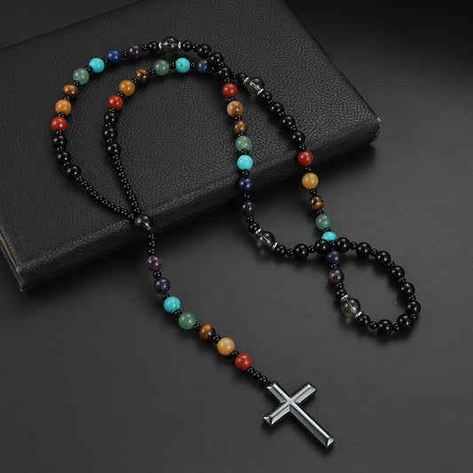 Multicolored beaded necklace with a silver cross pendant on a dark surface