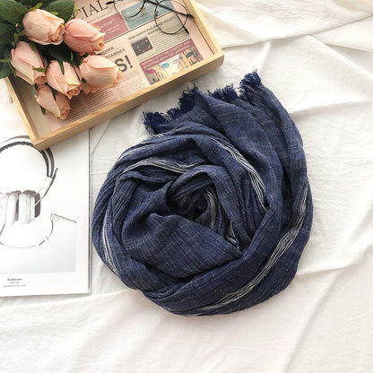 Blue scarf on a white surface with flowers and a newspaper in the background